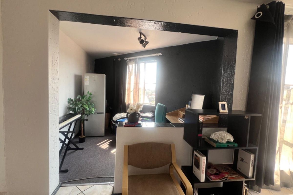 A multi-purpose living area featuring a partitioned space, neutral carpeting, and natural light through a window.