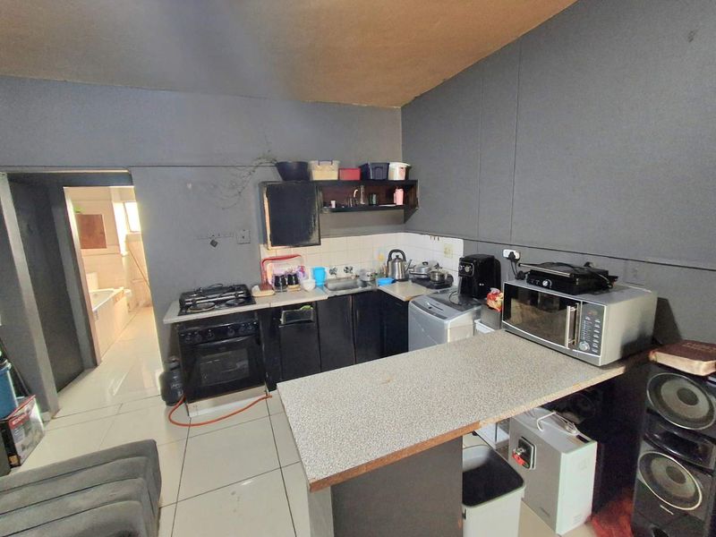 Compact kitchen featuring built-in cabinetry, a gas stove with oven, and a breakfast counter, with a view into the adjacent bathroom.