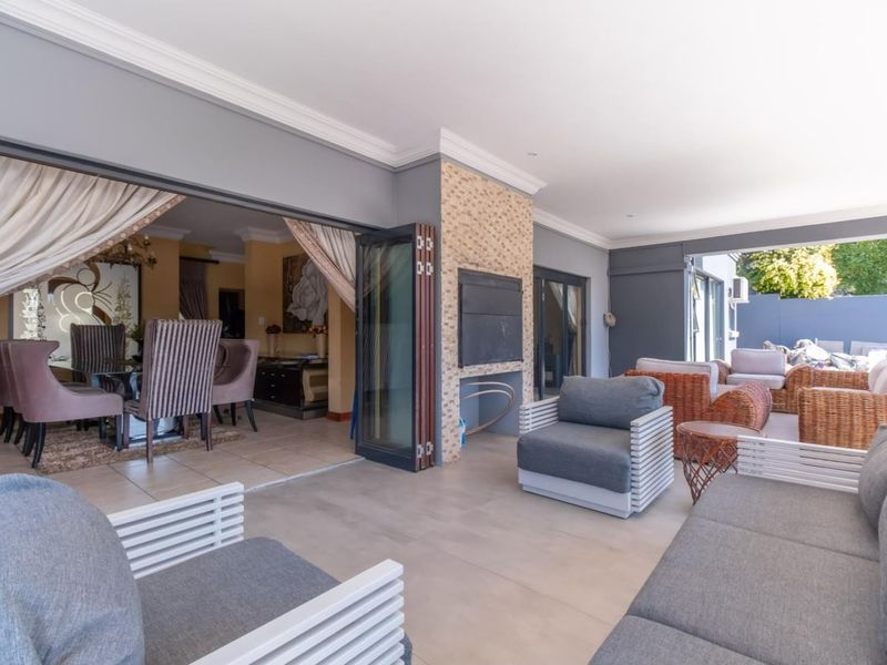 Spacious covered patio featuring a built-in braai, modern tiled flooring, and seamless stacking doors that open into the interior living area.