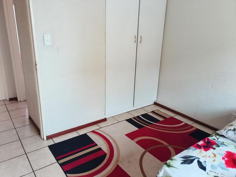 A bedroom featuring tiled flooring and a built-in wardrobe with white doors.