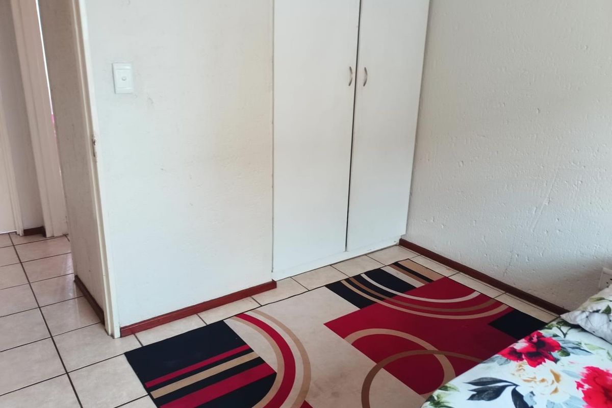 A bedroom featuring tiled flooring and a built-in wardrobe with white doors.