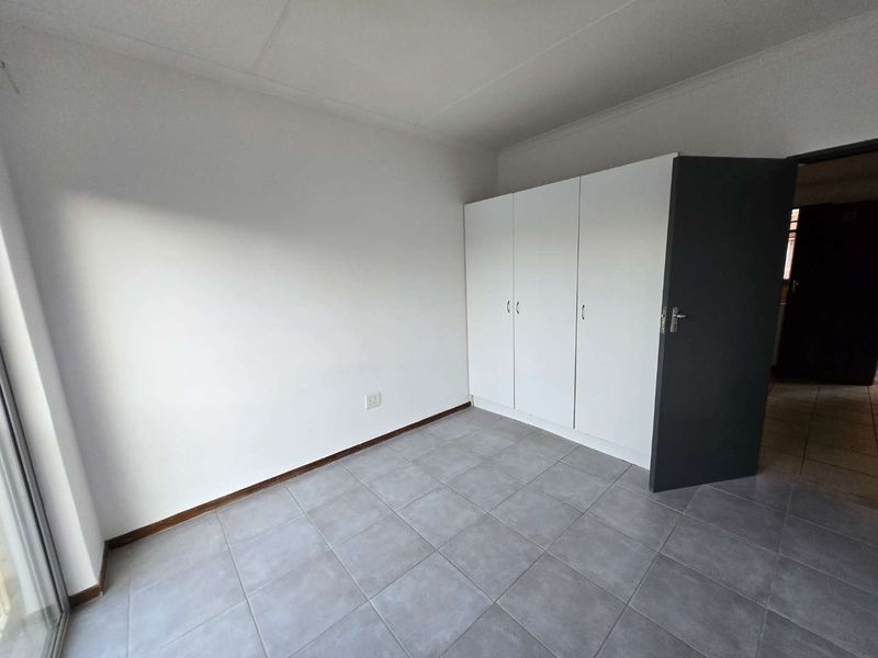 A clean, empty bedroom featuring neutral tiled flooring and a functional built-in wardrobe, offering a blank canvas for personalization.
