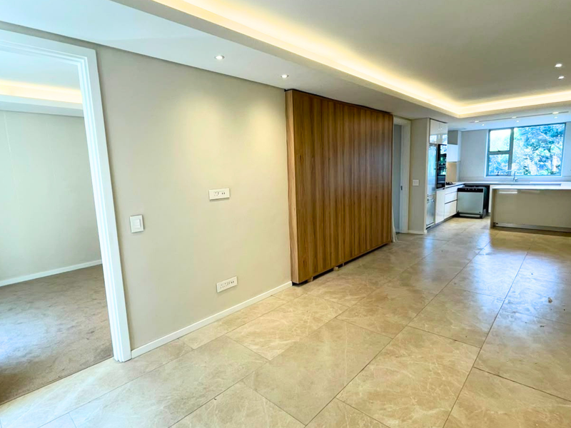 Spacious open-plan living area featuring modern stone flooring, recessed cove lighting, and a sleek integrated kitchen with built-in appliances.