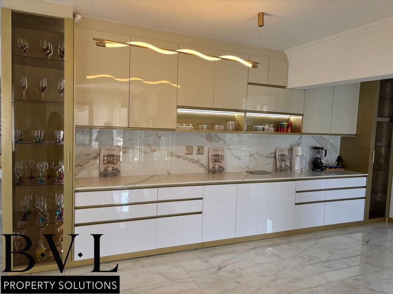 Modern kitchen featuring high-gloss cabinetry, marble-look countertops and splashback, integrated display shelving, and elegant under-cabinet lighting.