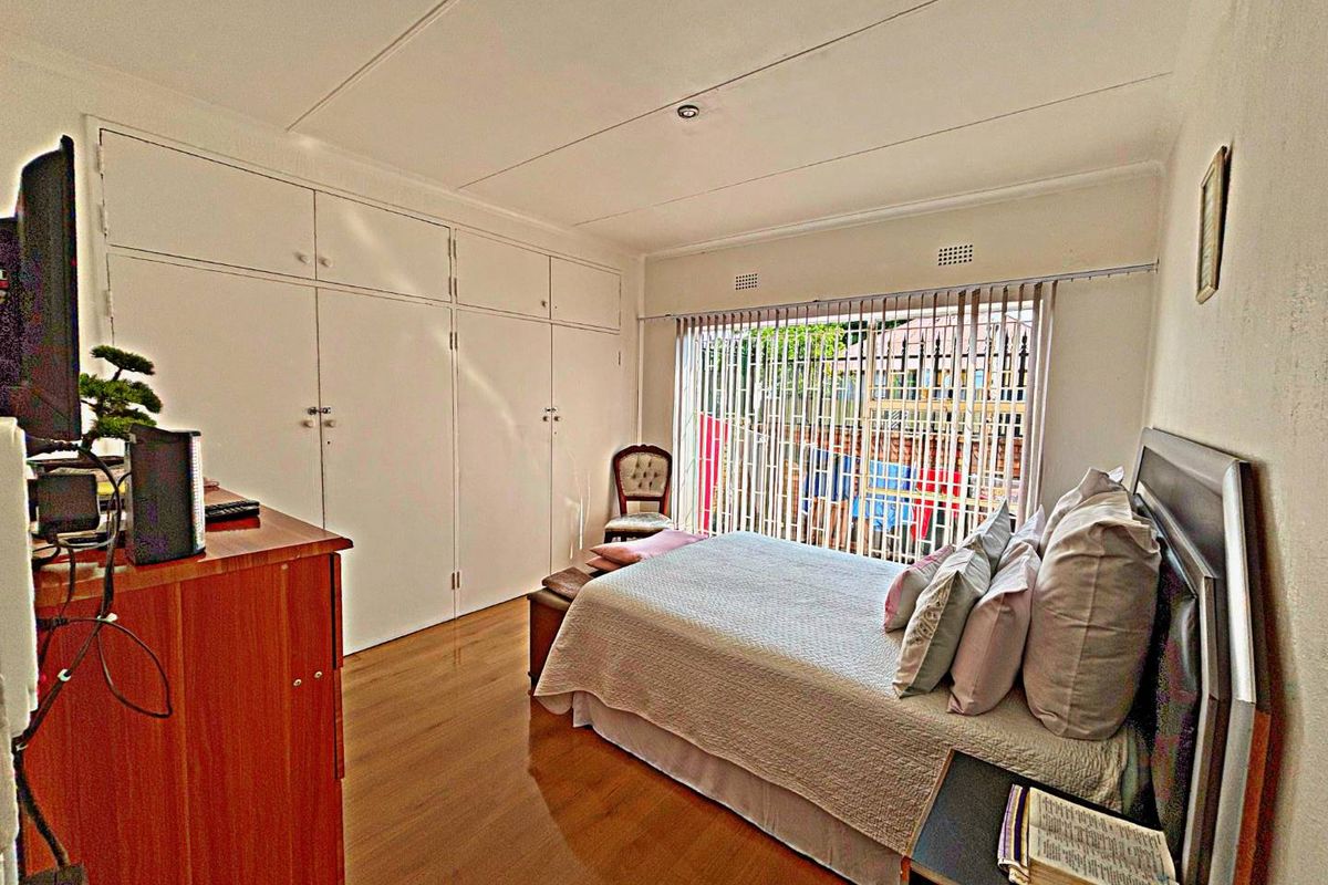 A bedroom featuring built-in floor-to-ceiling cabinetry, laminate wood flooring, and large sliding glass doors providing access to the exterior.