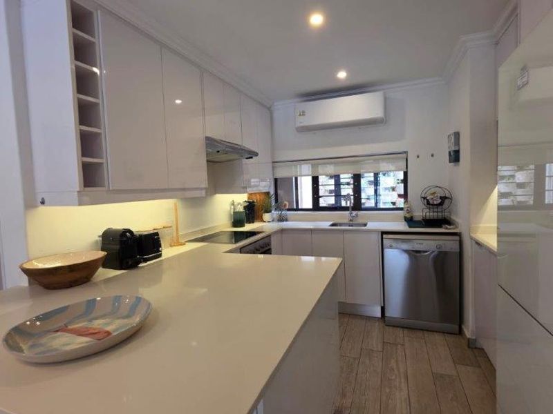 Modern kitchen featuring sleek glossy cabinetry, stone countertops, integrated appliances, and efficient under-cabinet lighting, complemented by durable tiled flooring.