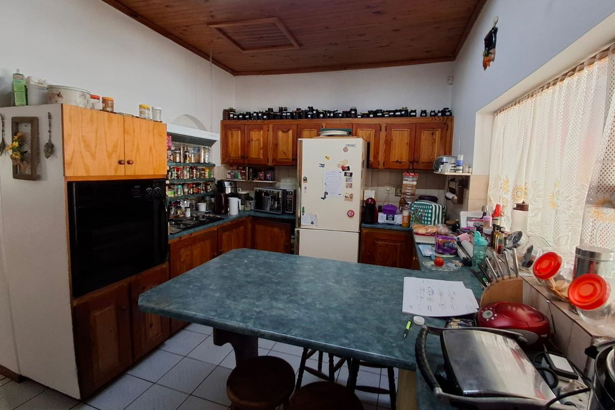 A functional kitchen featuring traditional wooden cabinetry, laminate countertops, and a timber ceiling, offering a classic layout with potential for modern updates.