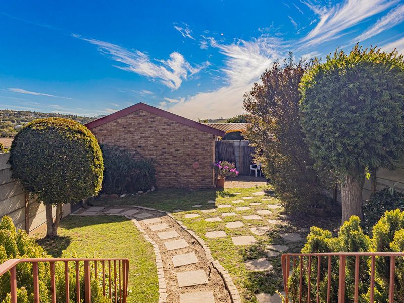 A private rear garden featuring a brick outbuilding, paved pathway, and established landscaping, offering a quiet outdoor space for the townhouse.