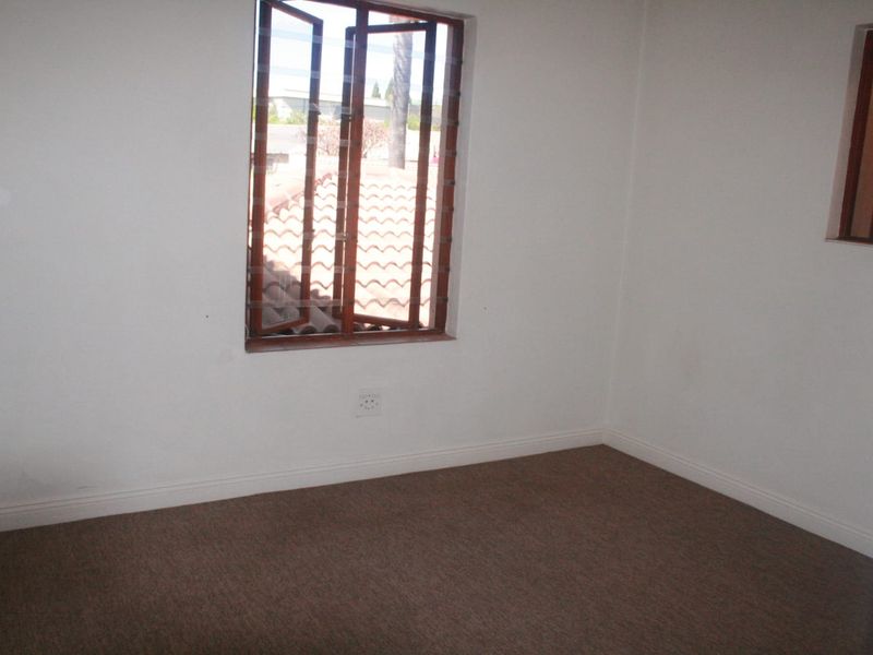 An empty bedroom featuring carpeted flooring, neutral walls, and a timber-framed casement window providing natural light.