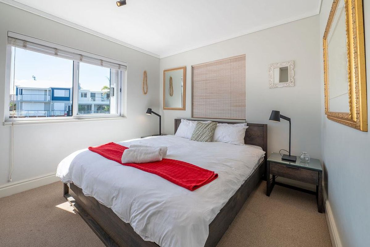 A well-lit bedroom featuring neutral carpeting, large windows with blinds, and clean wall finishes, offering a comfortable and bright living space.