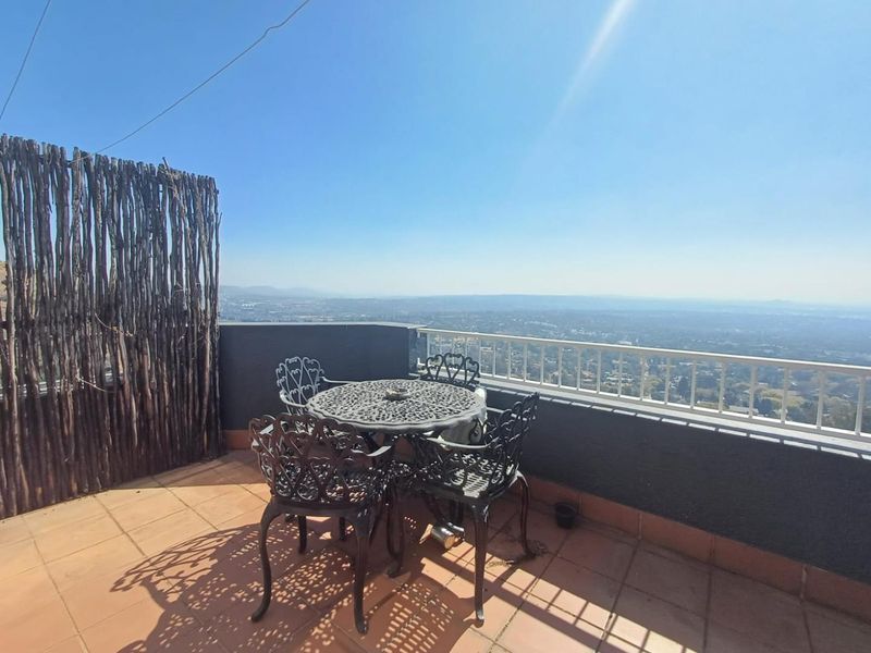 An elevated balcony featuring tiled flooring, a metal safety balustrade, and expansive panoramic views of the surrounding landscape.