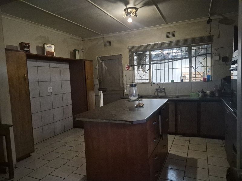 A dated kitchen featuring a central island, tiled flooring, and built-in cabinetry, offering significant potential for modernization and renovation.
