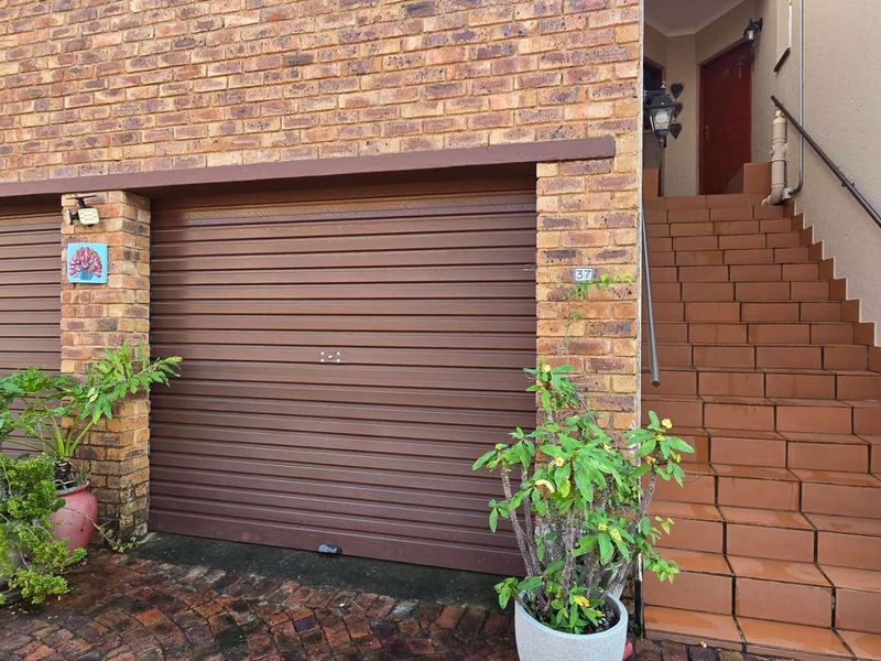 Front elevation of a townhouse featuring a double garage with roller doors and a tiled staircase leading to the main entrance.