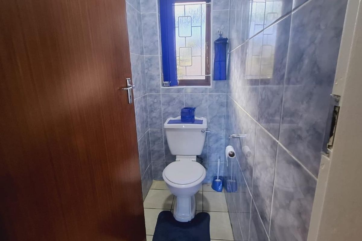 A compact guest bathroom featuring floor-to-ceiling blue marble-effect wall tiles, tiled flooring, and a standard toilet suite.