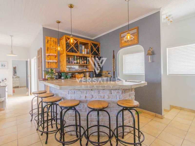 A dedicated bar area featuring a rustic brick counter with a stone top, integrated wooden wine storage, and pendant lighting.