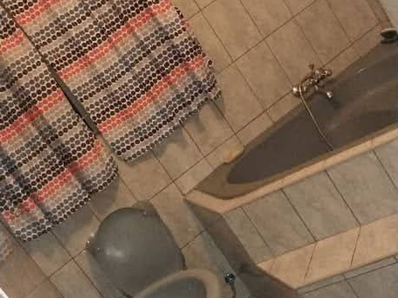 A dated bathroom featuring a pedestal basin, built-in bathtub, and full-height wall tiling.
