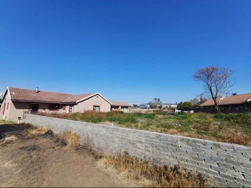 Rear view of the property showing a large, unlandscaped garden area enclosed by a brick boundary wall and the rear facade of the house.