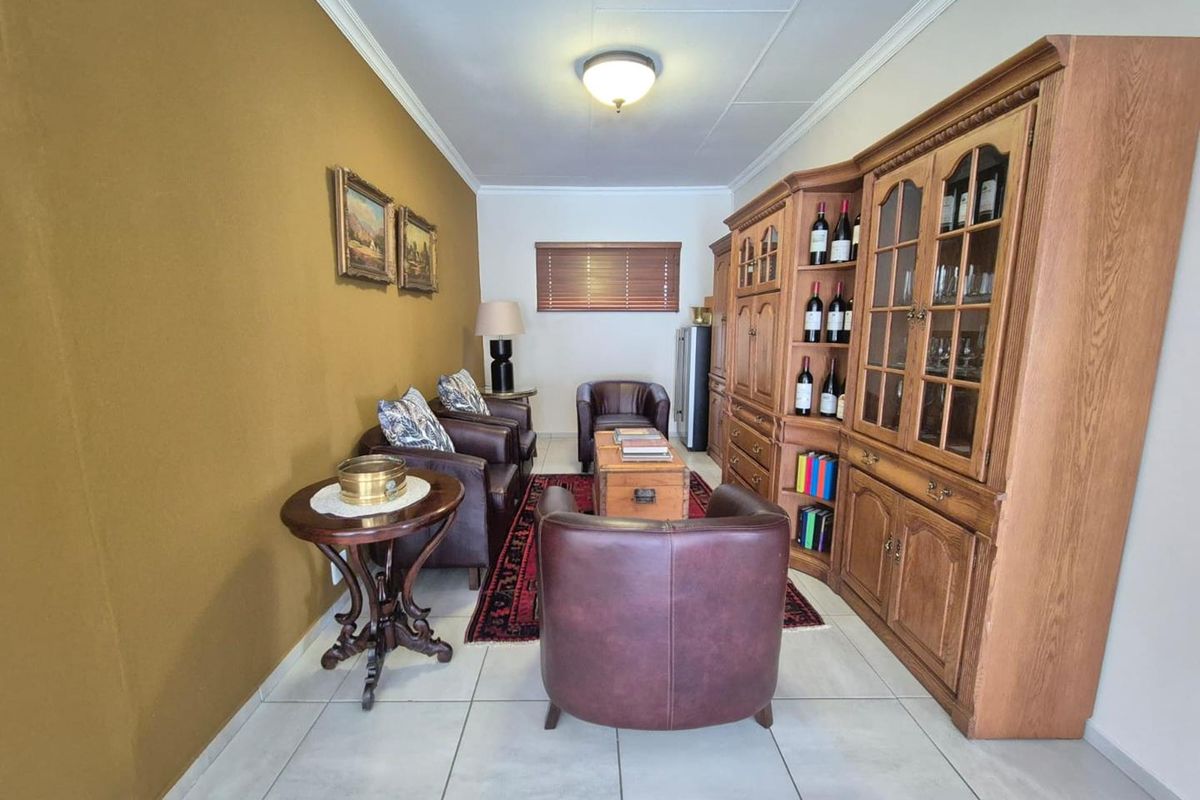 A cozy living room featuring tiled flooring, crown molding, and a large built-in wooden display cabinet.