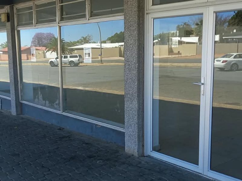 Front facade of a retail property featuring large glass display windows, aluminium framed entrance doors, and a paved walkway.