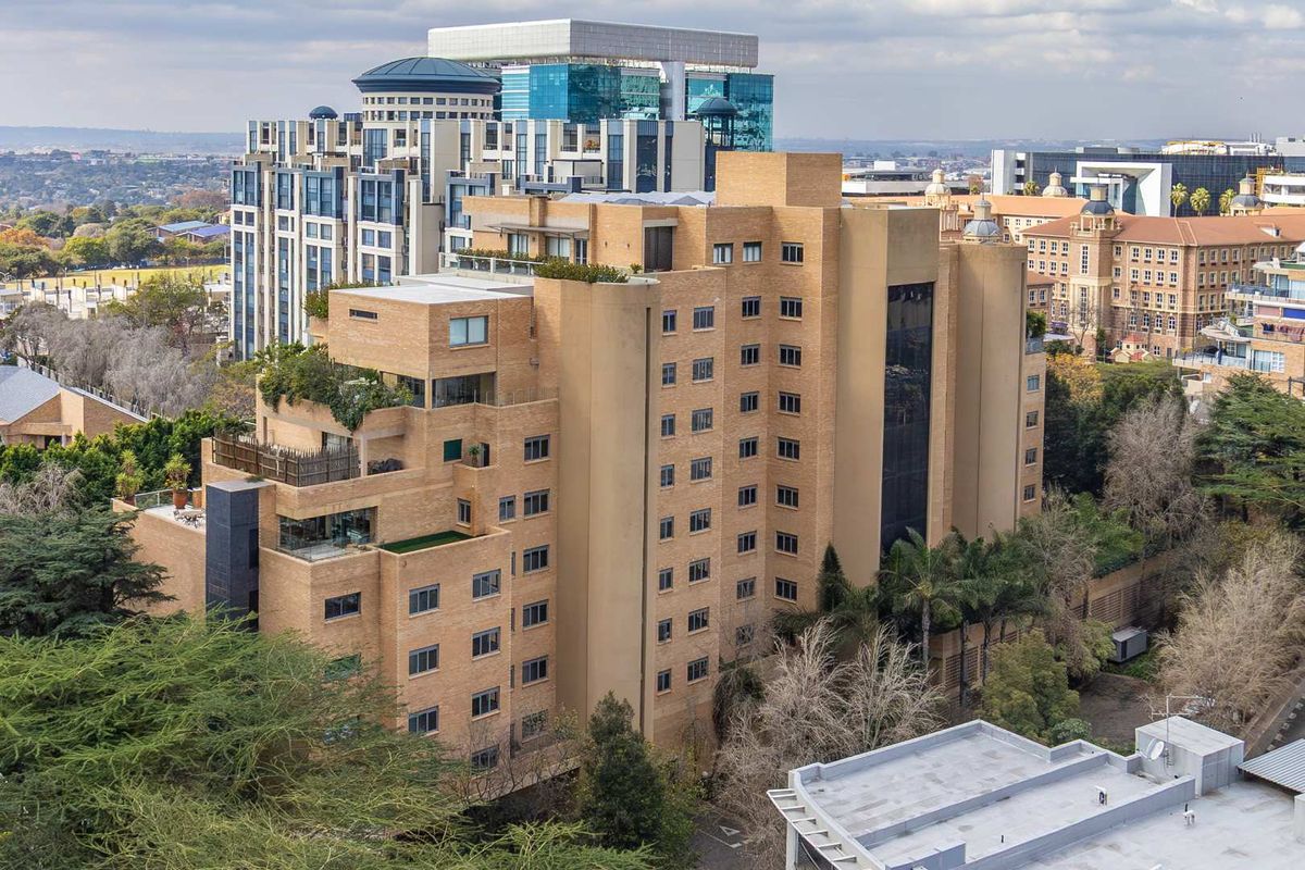 Aerial view of a multi-story brick penthouse building featuring multiple terraces and balconies set within an urban environment.