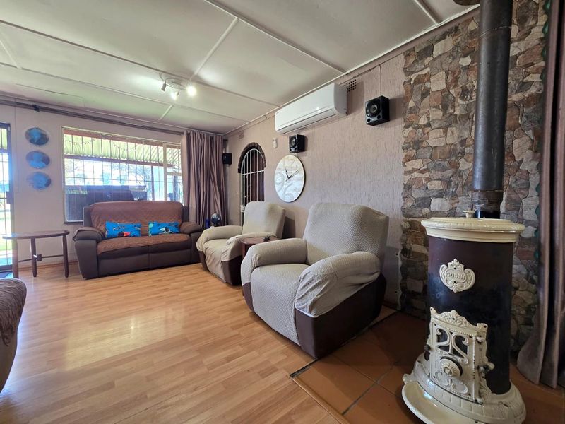 A cozy living room featuring a classic cast iron fireplace, stone accent wall, and split-system air conditioning, finished with durable laminate flooring.