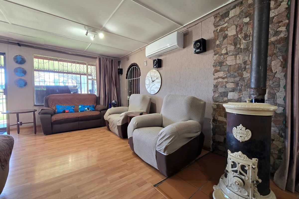 A cozy living room featuring a classic cast iron fireplace, stone accent wall, and split-system air conditioning, finished with durable laminate flooring.