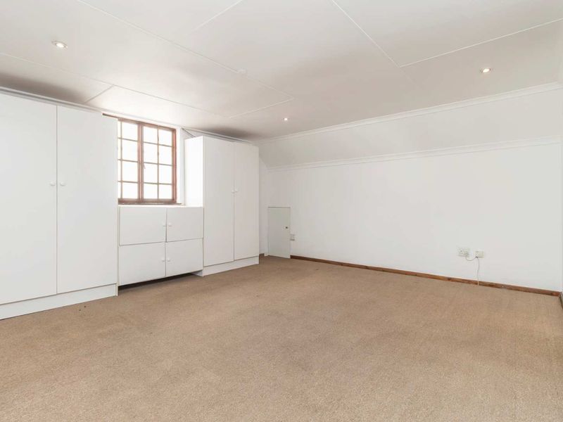 Spacious bedroom featuring neutral walls, built-in storage cupboards, recessed lighting, and carpeted flooring.