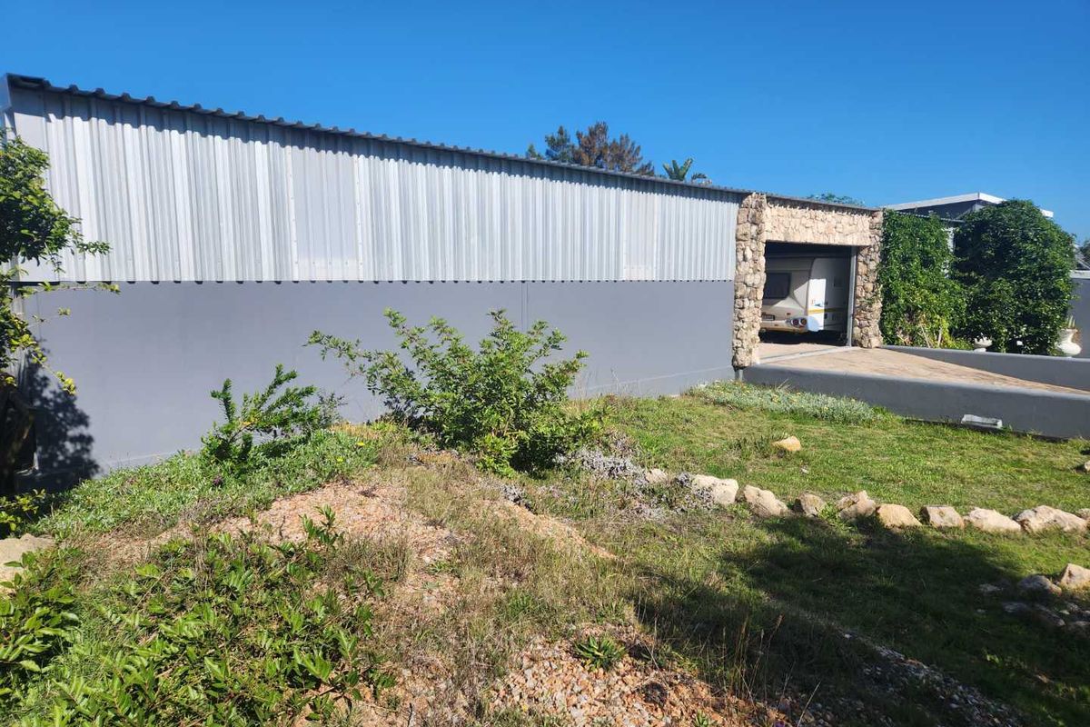 Exterior view of a large metal-clad outbuilding or garage structure featuring stone-clad entrance detailing and a paved driveway area.