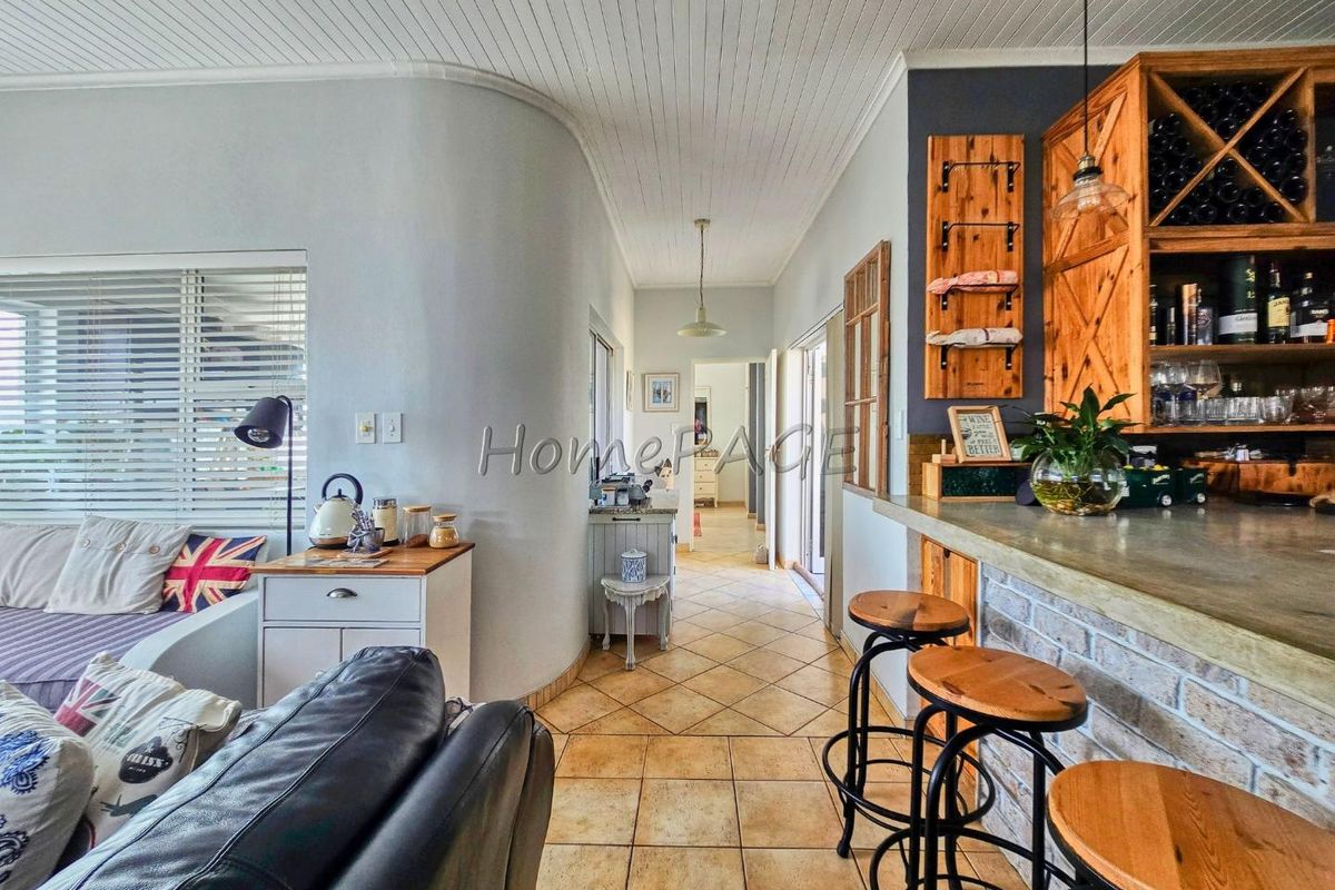 A living area featuring a built-in bar with a stone counter, brick base, and integrated wine storage, complemented by tiled flooring and a tongue-and-groove ceiling.