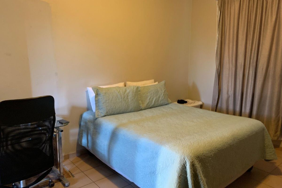 A functional bedroom featuring tiled flooring and neutral wall finishes, providing a simple and practical living space.