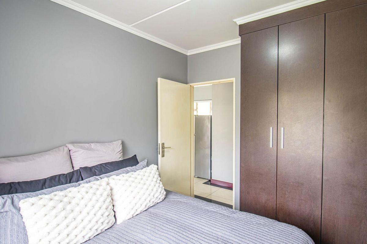 A well-maintained bedroom featuring built-in dark wood cabinetry and neutral grey wall finishes, providing a clean and functional living space.