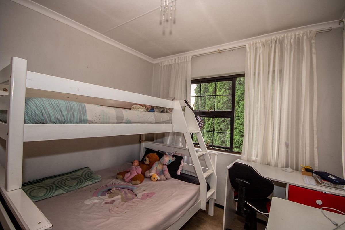 A functional bedroom featuring a window with curtain tracks and neutral wall finishes, suitable for a child or guest room.