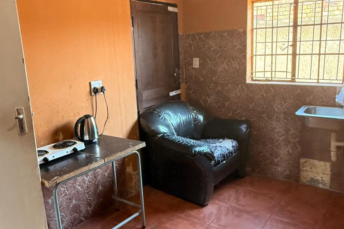 A compact kitchen area featuring tiled flooring, a stainless steel sink, and tiled splashbacks, requiring cosmetic updates to improve the overall finish.