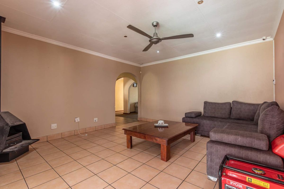Spacious living area featuring tiled flooring, a built-in fireplace, and an arched doorway leading to adjacent rooms.