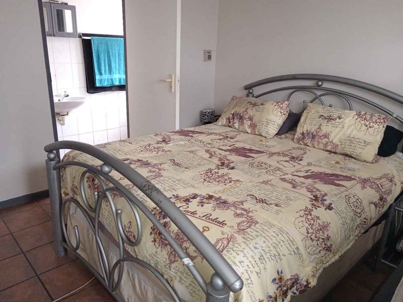 A bedroom featuring tiled flooring and direct access to an en-suite bathroom.