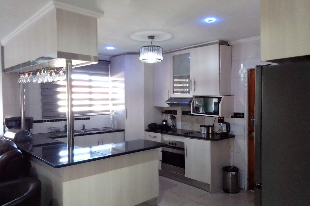 Modern kitchen featuring granite countertops, built-in oven, extractor fan, and a functional breakfast bar with integrated lighting.