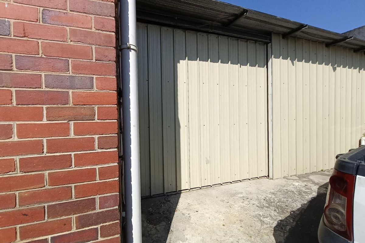Exterior view of an industrial building featuring corrugated metal cladding, brick wall section, and a concrete apron area.