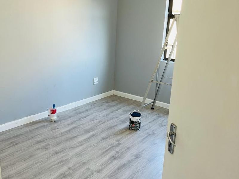 A clean, empty bedroom featuring modern grey laminate flooring and neutral painted walls, ready for personalization.