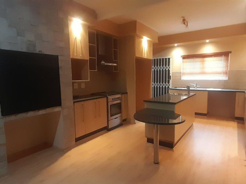 Spacious kitchen featuring modern cabinetry, stone countertops, a central island with breakfast bar, and a distinctive stone feature wall with integrated lighting.