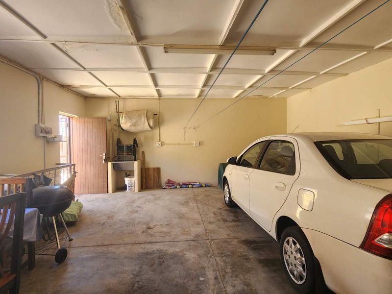A spacious garage featuring a concrete floor, utility sink, and exposed ceiling tiles, providing ample storage or parking space.