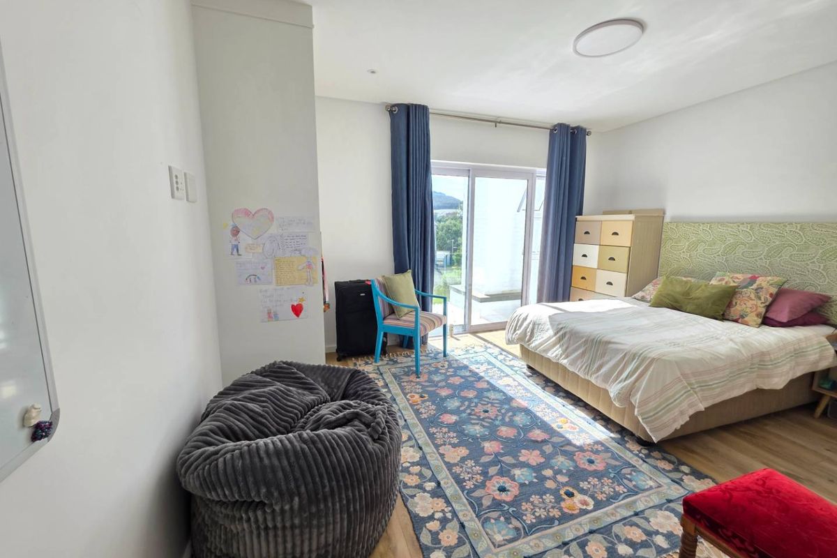 Spacious bedroom featuring laminate flooring and a sliding glass door providing access to an outdoor area, offering natural light and ventilation.