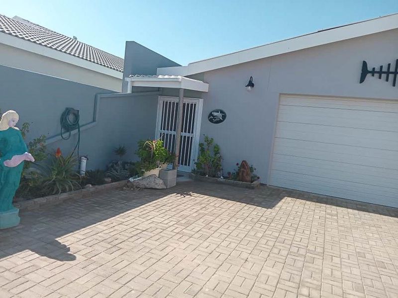 Front exterior view of the property featuring a paved driveway, single garage door, and a secure entrance gate.