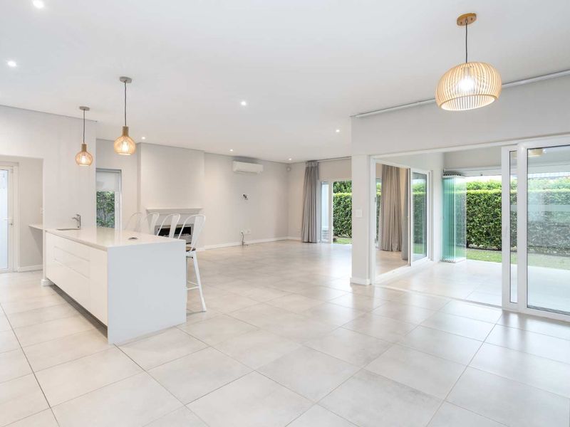 Spacious open-plan living area featuring a modern kitchen island, built-in fireplace, and seamless flow to the outdoor patio through large sliding glass doors.