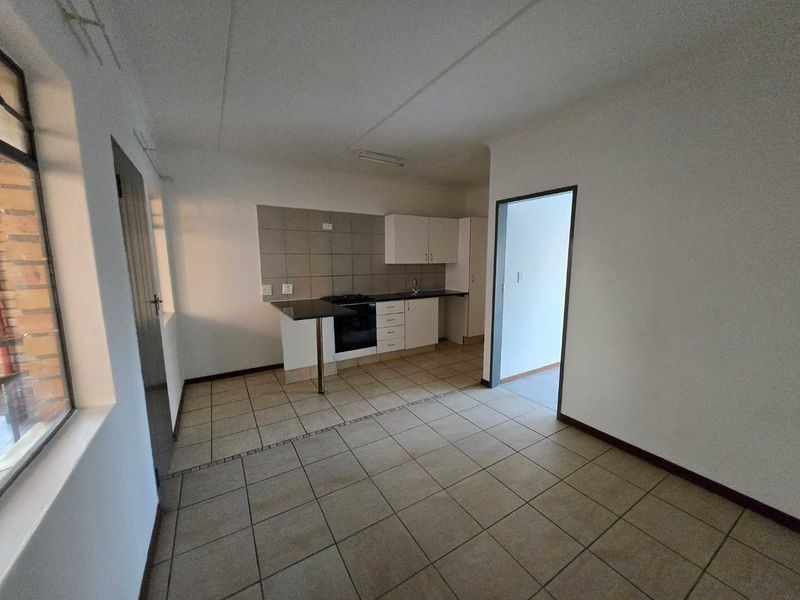 A functional, empty kitchen featuring tiled flooring, built-in cabinetry, a hob, and an oven, offering a clean canvas for potential updates.