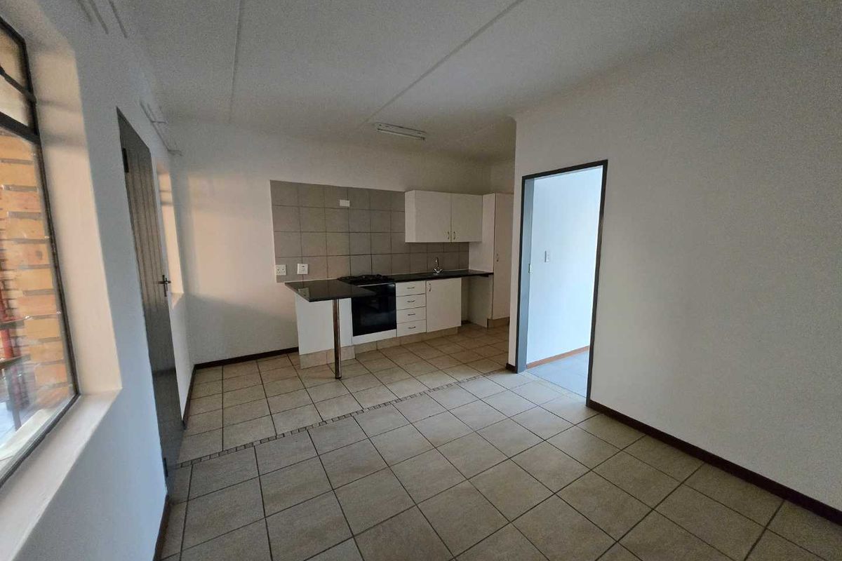 A functional, empty kitchen featuring tiled flooring, built-in cabinetry, a hob, and an oven, offering a clean canvas for potential updates.