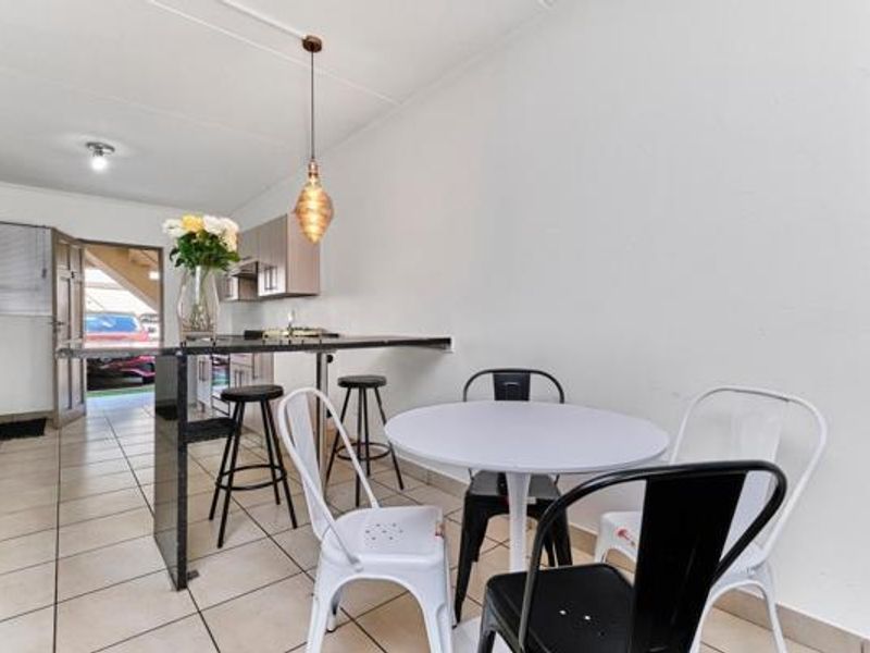 Open plan kitchen and dining area featuring tiled flooring, a built-in breakfast bar, and modern pendant lighting.