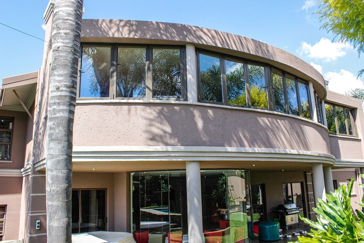 A view of the rear exterior of the house, featuring a curved architectural design, large windows, and a covered patio area.