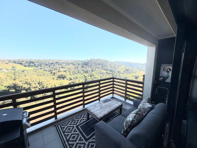 Covered balcony featuring tiled flooring and a timber balustrade, offering expansive elevated views of the surrounding landscape.