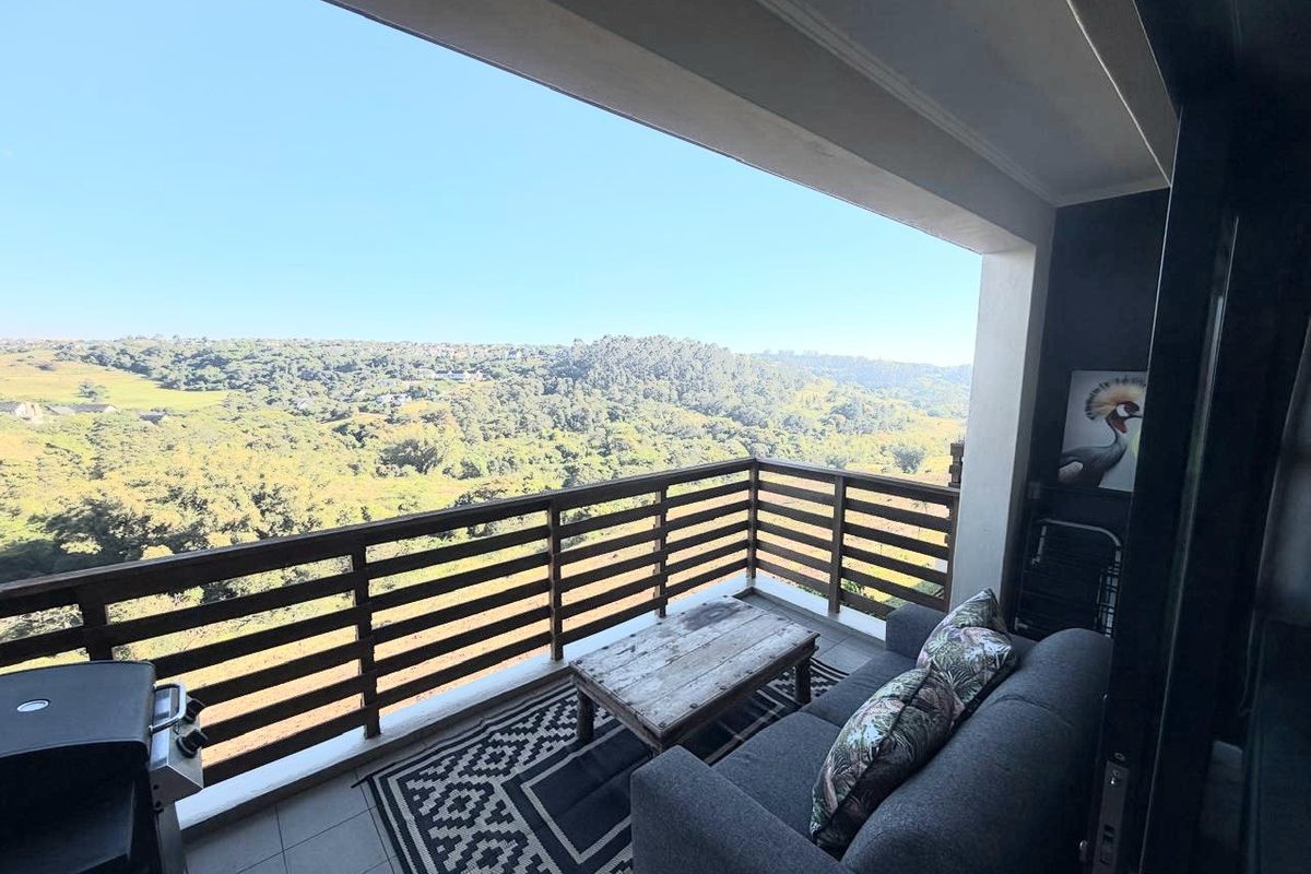 Covered balcony featuring tiled flooring and a timber balustrade, offering expansive elevated views of the surrounding landscape.