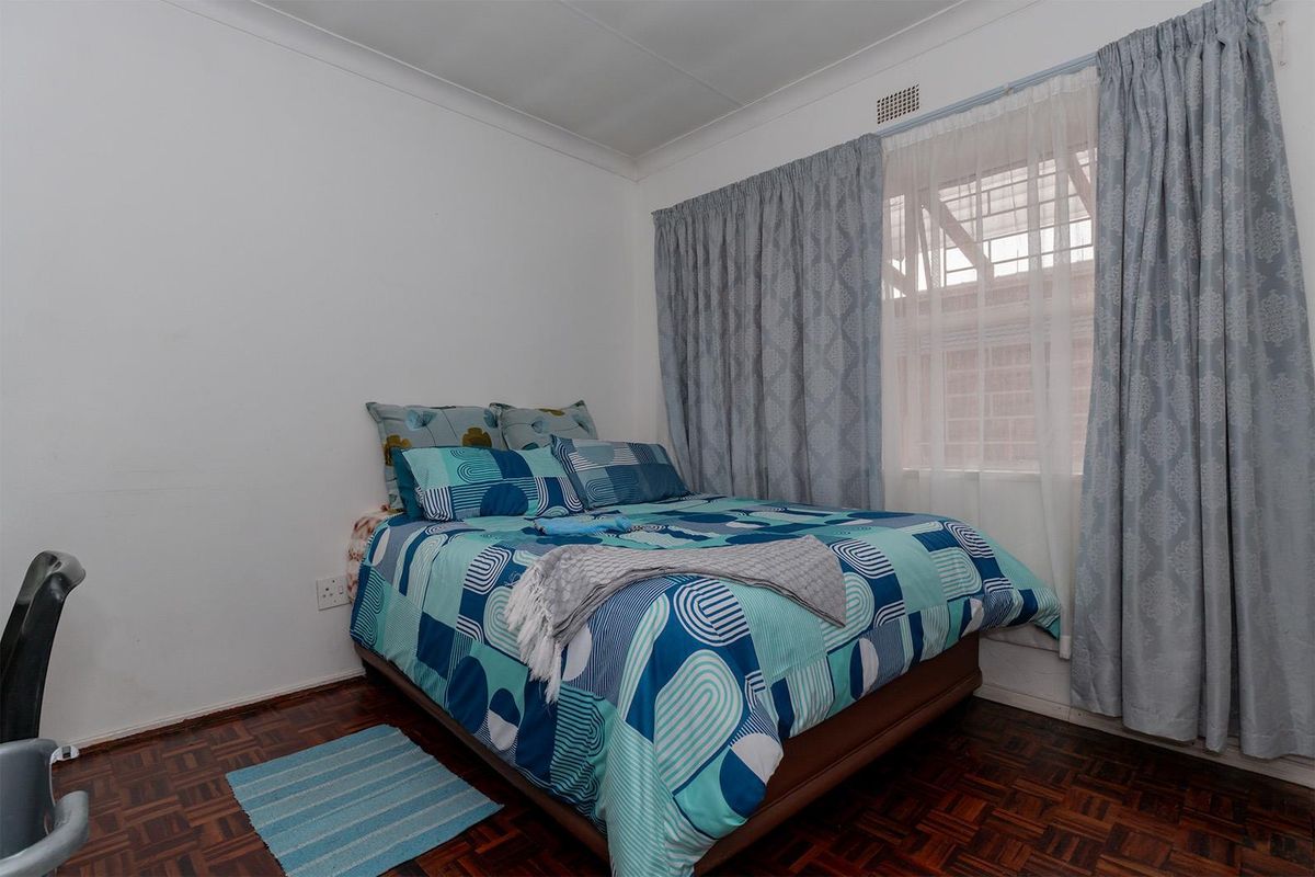 A bedroom featuring classic parquet flooring and a window with installed curtain tracks.